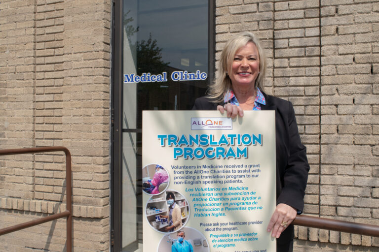 Volunteers in Medicine's Kelly Ranieli with a sign about the nonprofit's medical translation service.