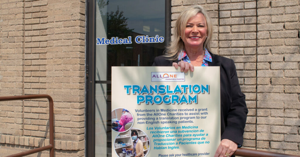 Volunteers in Medicine's Kelly Ranieli with a sign about the nonprofit's medical translation service.
