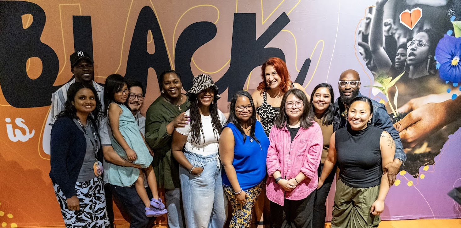 Staff members at Grand Victoria Foundation pose in front of a mural at a foundation-hosted event called Black Abundance Convening